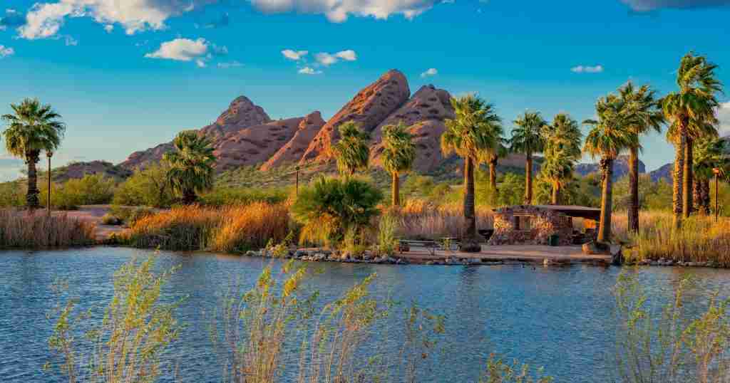 a lake with palm trees and mountains in the background